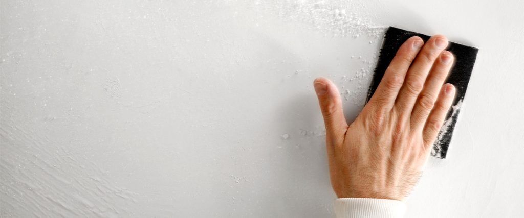 Use papel de lija para lijar la superficie de la pared. nivelación
